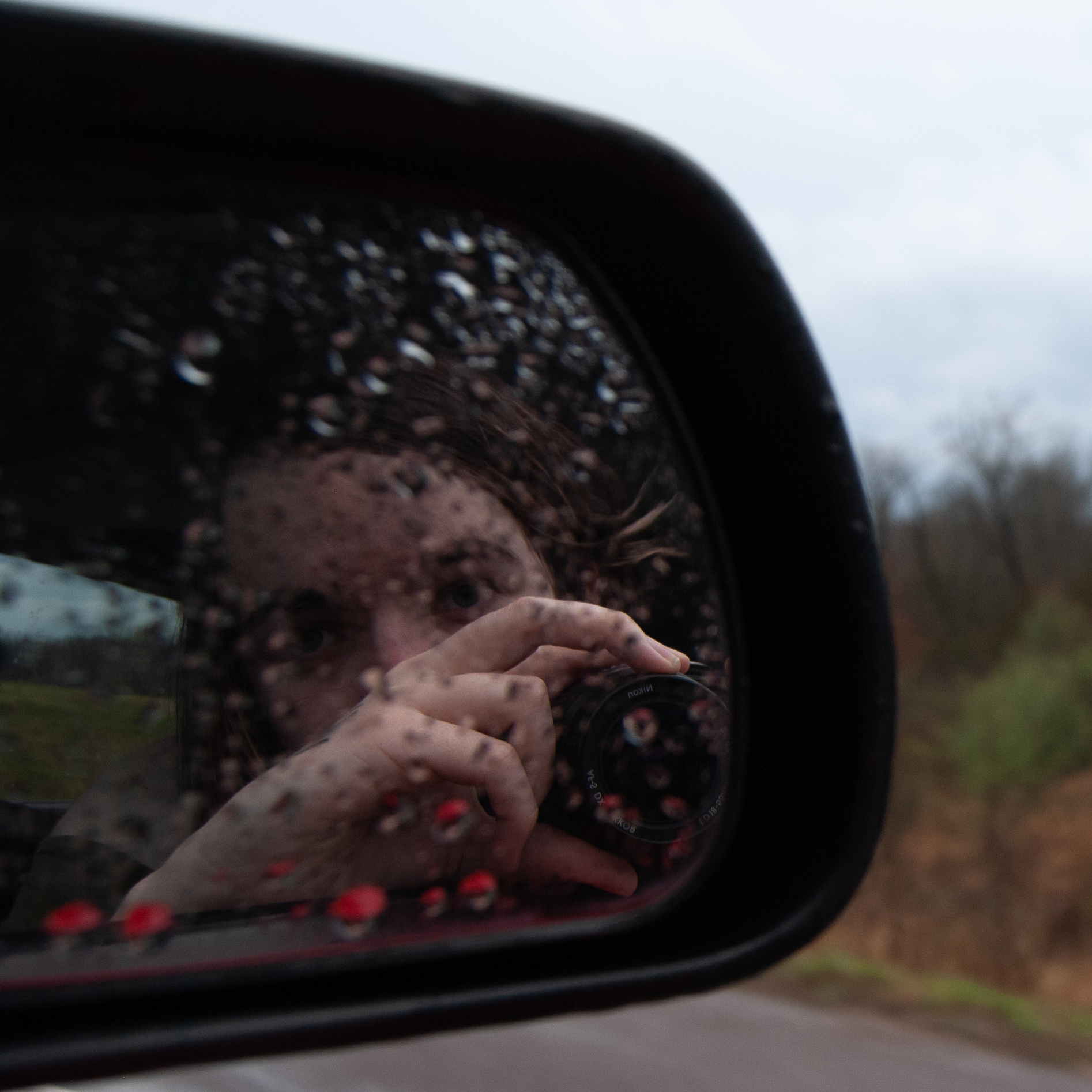 a reflection of a woman in a car mirror